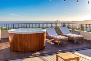 uma grande banheira de madeira sentada num deque com 2 cadeiras em Ocean view Luxury Retreat em El Pueblito
