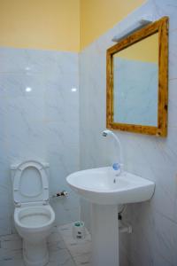 La salle de bains est pourvue d'un lavabo, de toilettes et d'un miroir. dans l'établissement Vibrant Haven ~ Deux, à Kilifi