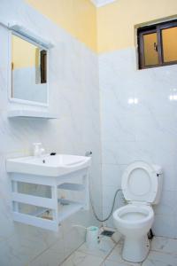 La salle de bains blanche est pourvue d'un lavabo et de toilettes. dans l'établissement Vibrant Haven ~ Deux, à Kilifi