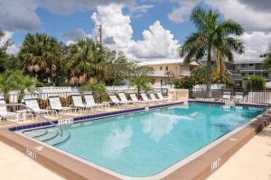 einen großen Pool mit Stühlen und Palmen in der Unterkunft Bridgeport Condo 209 in Bradenton Beach