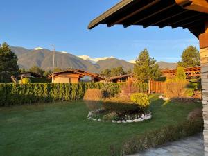un patio con valla y césped con montañas al fondo en Villa - VALL DI VALL in Pirin Golf & Country Club, en Razlog