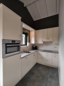een keuken met witte kasten en een fornuis met oven bij Luxe familiehuis 8p nabij bos en hei op de Veluwe in Putten