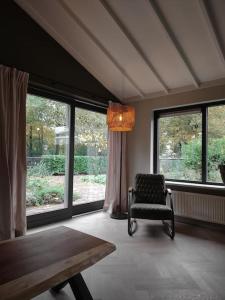 een kamer met een stoel, een tafel en ramen bij Luxe familiehuis 8p nabij bos en hei op de Veluwe in Putten