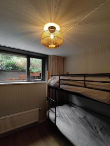 een slaapkamer met 2 stapelbedden en een kroonluchter bij Luxe familiehuis 8p nabij bos en hei op de Veluwe in Putten