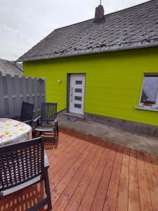 ein grünes Gebäude mit zwei Stühlen und einem Tisch auf einer Terrasse in der Unterkunft Haus Rosi in Lutzerath