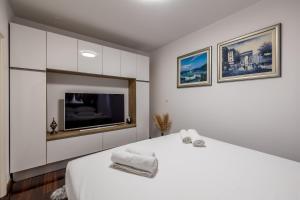 ein weißes Schlafzimmer mit einem großen Bett und einem TV in der Unterkunft Noemi Luxury Apartment in Solin
