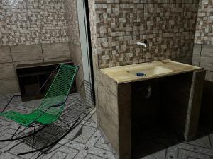 a green chair sitting next to a sink in a bathroom at Condomínio luiza in Rio Branco