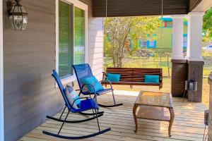 - deux chaises bleues et une table sur une terrasse couverte dans l'établissement Red Door Cottage, à Waco