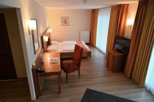 ein Hotelzimmer mit einem Bett und einem Tisch sowie einem Zimmer in der Unterkunft Landhotel Krummenweg in Ratingen