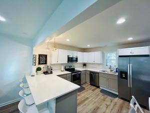 uma cozinha com armários brancos e um frigorífico de aço inoxidável em Modern Home Near Uptown CLT, Airport and More em Charlotte