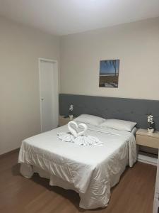 a bedroom with a large white bed with white sheets at Hotel Treviso in Linhares