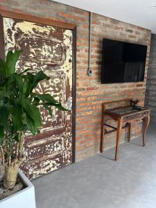 um quarto com uma porta, uma mesa e uma televisão em Pousada O Bosque Casa 1 em Imbituba