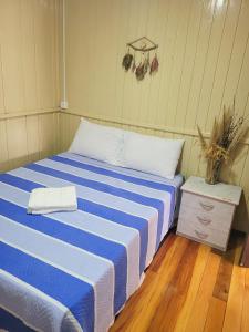 a bedroom with a bed with a blue and white stripes at Pousada Justi Oliveira in Louro Müller