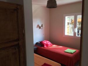 ein Schlafzimmer mit einem roten Bett und einem Fenster in der Unterkunft SEJOUR DETENTE BALAGNE ENTRE MER ET MONTAGNE in Urtaca