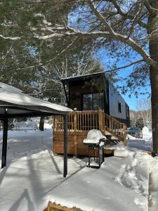 a cabin with a deck in the snow at Micro chalet Le Boisé ! in Saint Zenon