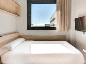 ein Schlafzimmer mit einem weißen Bett und einem Fenster in der Unterkunft Livensa Living Studios Málaga Feria in Málaga
