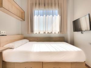 ein Schlafzimmer mit einem großen weißen Bett und einem Fenster in der Unterkunft Livensa Living Studios Málaga Feria in Málaga