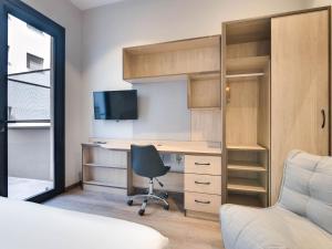 1 dormitorio con escritorio con silla y TV en Livensa Living Studios Málaga Feria, en Málaga