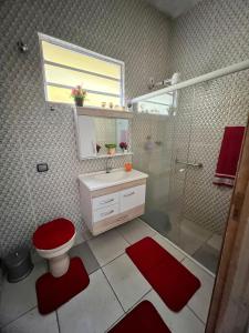 uma casa de banho com um WC vermelho e um chuveiro em A CASA DE IRENE II em Aparecida