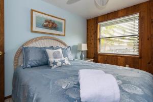 a bedroom with a bed with blue sheets and a window at Azure Seas in Anna Maria