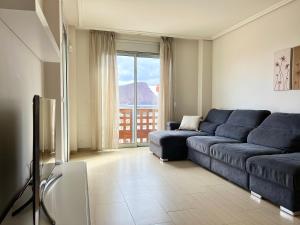 a living room with a blue couch and a large window at Ocean view two bedroom apartment in Granadilla de Abona