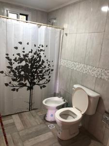 baño con aseo y cortina de ducha con árbol en 12 Olivos Cabañas en San Rafael