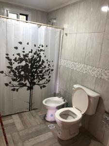 a bathroom with a toilet and a shower curtain with a tree at 12 Olivos Cabañas in San Rafael