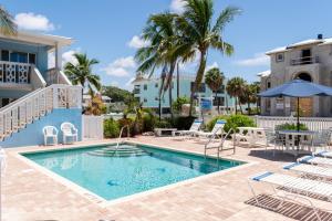 Una piscina con sillas y una mesa y un edificio. en Anna Maria Beach Place, Unit 6, en Holmes Beach