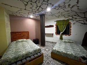 um quarto com 2 camas e um mural de árvore no tecto em El castillo santa em Santa Bárbara