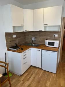 a kitchen with white cabinets and a sink and a microwave at Brand new apartment in the heart of Bratislava in Bratislava