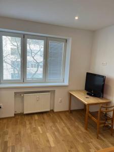 a room with a desk with a television and two windows at Brand new apartment in the heart of Bratislava in Bratislava