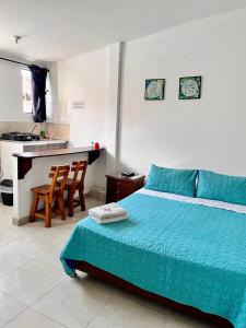 Cet appartement comprend une chambre avec un lit bleu et une cuisine. dans l'établissement Acogedor Apartaestudio en el Centro de Pereira, à Pereira