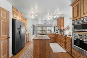 a large kitchen with wooden cabinets and a black refrigerator at Uptown Cabin Home with Views HotTub near Trails in Sedona