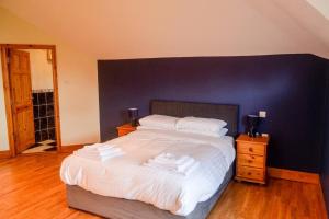 a bedroom with a large white bed with a blue wall at The Mountain Lodge Slievenamon spacious 4 bedroom house in Cloneen