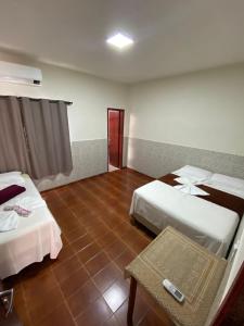 ein Hotelzimmer mit 2 Betten und einem Tisch in der Unterkunft Casa Temporada Espaço Vip in Barra do Garças