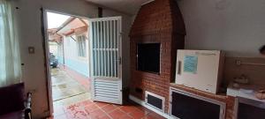 a living room with a brick fireplace and a white refrigerator at Casa Praia Mongaguá in Mongaguá