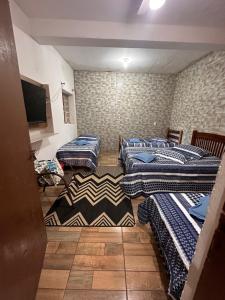 een kamer met 4 bedden en een flatscreen-tv bij A CASA DE IRENE I in Aparecida