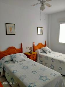een slaapkamer met 2 bedden en een plafondventilator bij Playa de La Barrosa La Almadraba IV Fase "Interior" B-3 in Chiclana de la Frontera