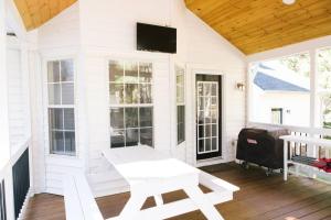 a white porch with a bench and a flat screen tv at Peaceful Haven on Outskirts in Wake Forest