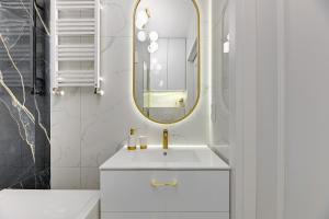 a bathroom with a white sink and a mirror at Nadmotławie Deluxe 2 Sauna & Siłownia by Grand Apartments in Gdańsk