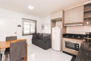 cocina con sofá, mesa y nevera en Apartamento Completo e Confortável em Bento 02, en Bento Gonçalves