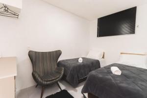 Habitación con 2 camas, silla y TV. en Apartamento Completo e Confortável em Bento 02, en Bento Gonçalves