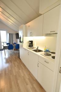 eine Küche mit weißen Schränken und einem Tisch mit blauen Stühlen in der Unterkunft Vakantie apppartement DE HAAN Park Zeepolder in De Haan