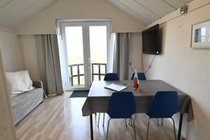 - un salon avec une table à manger et des chaises bleues dans l'établissement Vakantie apppartement DE HAAN Park Zeepolder, au Coq
