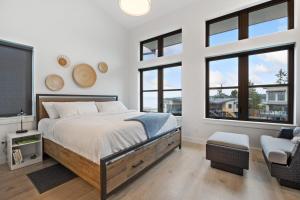 a bedroom with a bed and a chair and windows at The Beach Haven at THE BEACH HOUSE in Campbell River