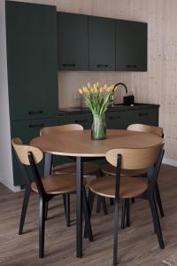 a kitchen with a wooden table with chairs and a vase of flowers at Rest h0me 