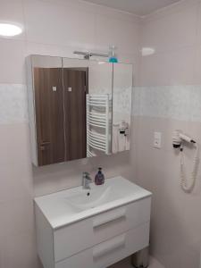 a white bathroom with a sink and a mirror at Prime Apartment Heviz in Hévíz