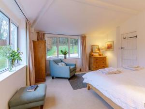 a bedroom with a bed and a chair and window at 4 Bed in Monmouth 42868 in Cwmcarvan