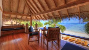 a dining room with a table and a view of the ocean at Etu Moana Boutique Beach Villas - Adults Only in Arutanga