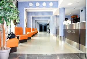 un vestíbulo vacío con sillas naranjas y un pasillo en East Time Hotel, en Minsk